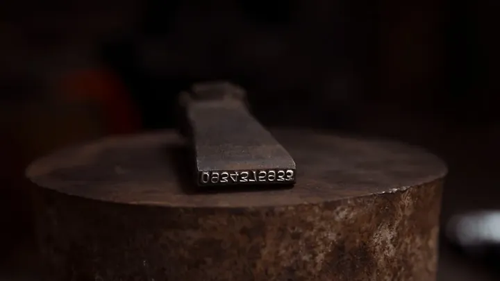 A worn maker's stamp on dark metal