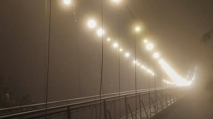 A lit suspension bridge running into fog
