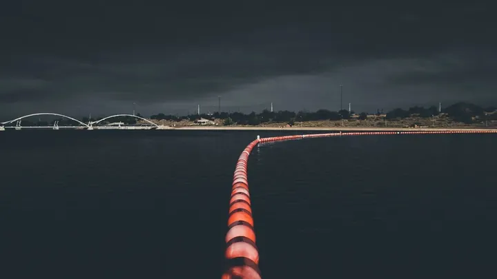 A line of marker floats curving away across dark water
