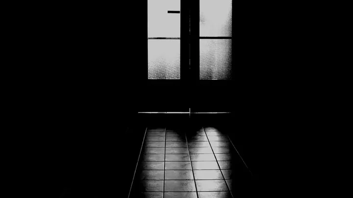 A backlit doorway at the end of a dark hall