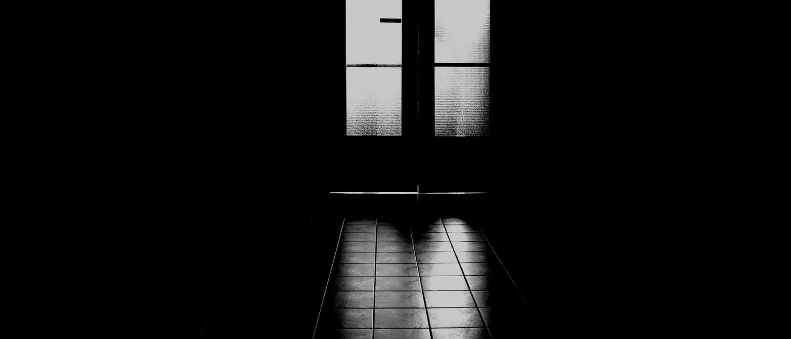 A backlit doorway at the end of a dark hall
