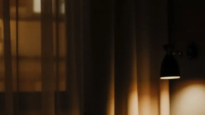 An empty bed lit by one lamp at night