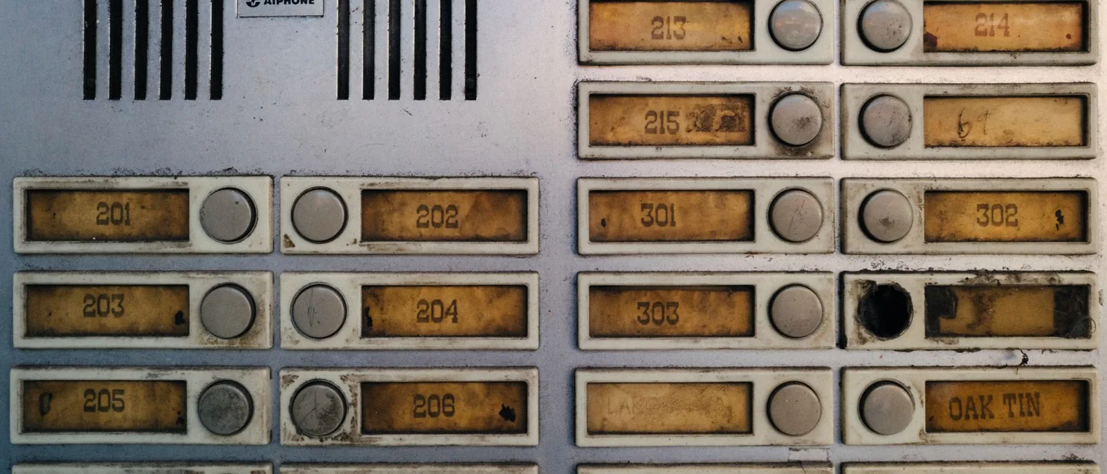 A worn intercom panel with labelled buttons