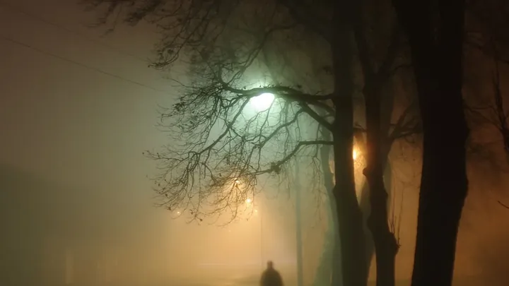A figure in fog under a streetlight