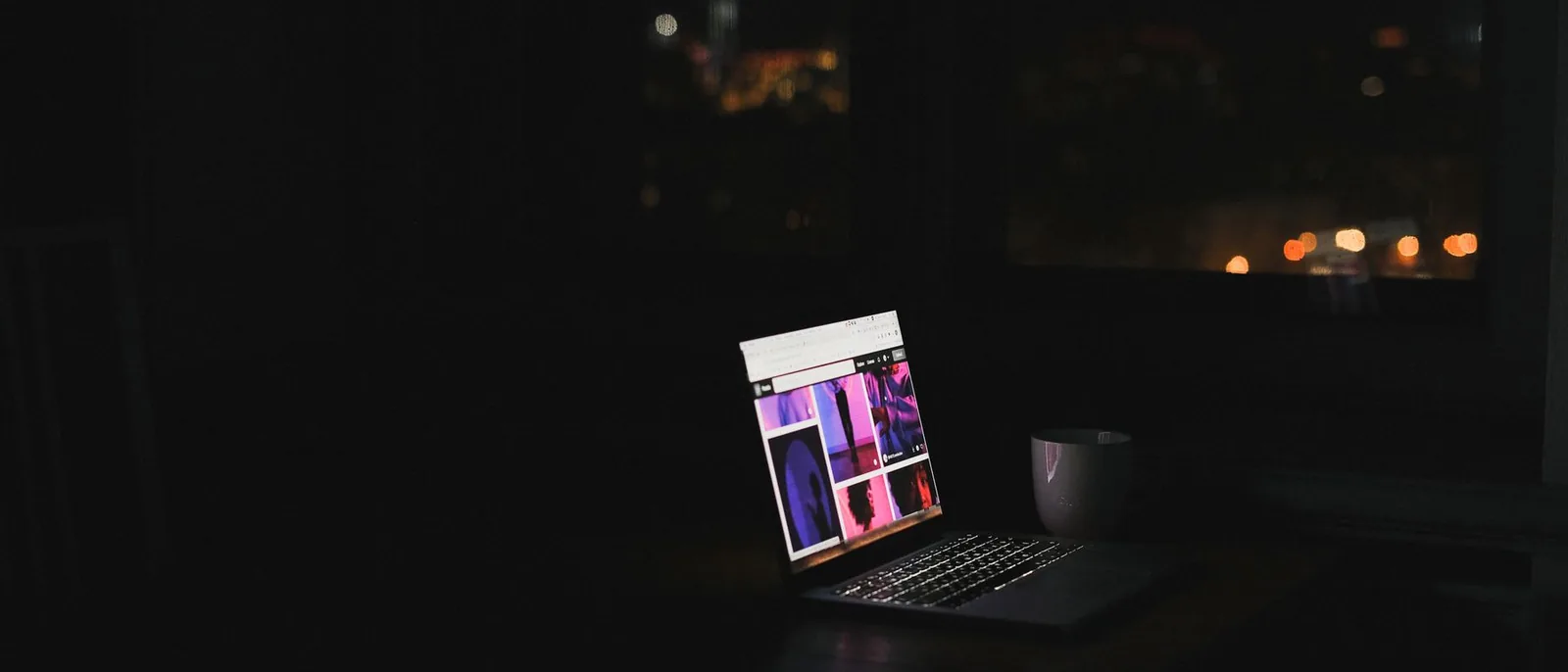 A single lit laptop in an otherwise dark room